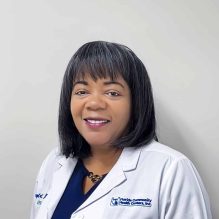 Headshot of Sheryl Timol, Family Nurse Practitioner, smiling in a white FCHC lab coat.